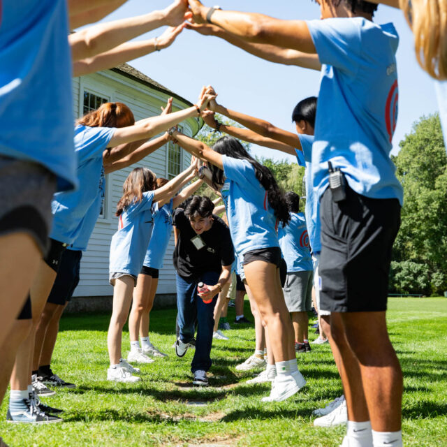 A student running under a group of student's raised arms.