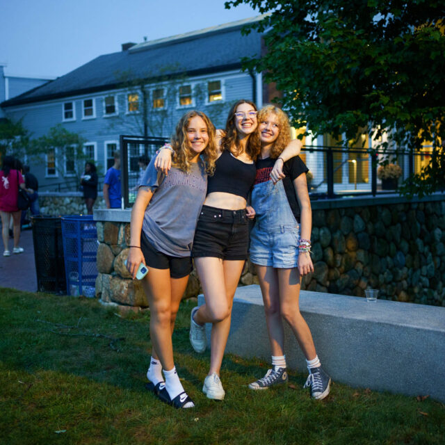 Three girls posing for a photo outside.