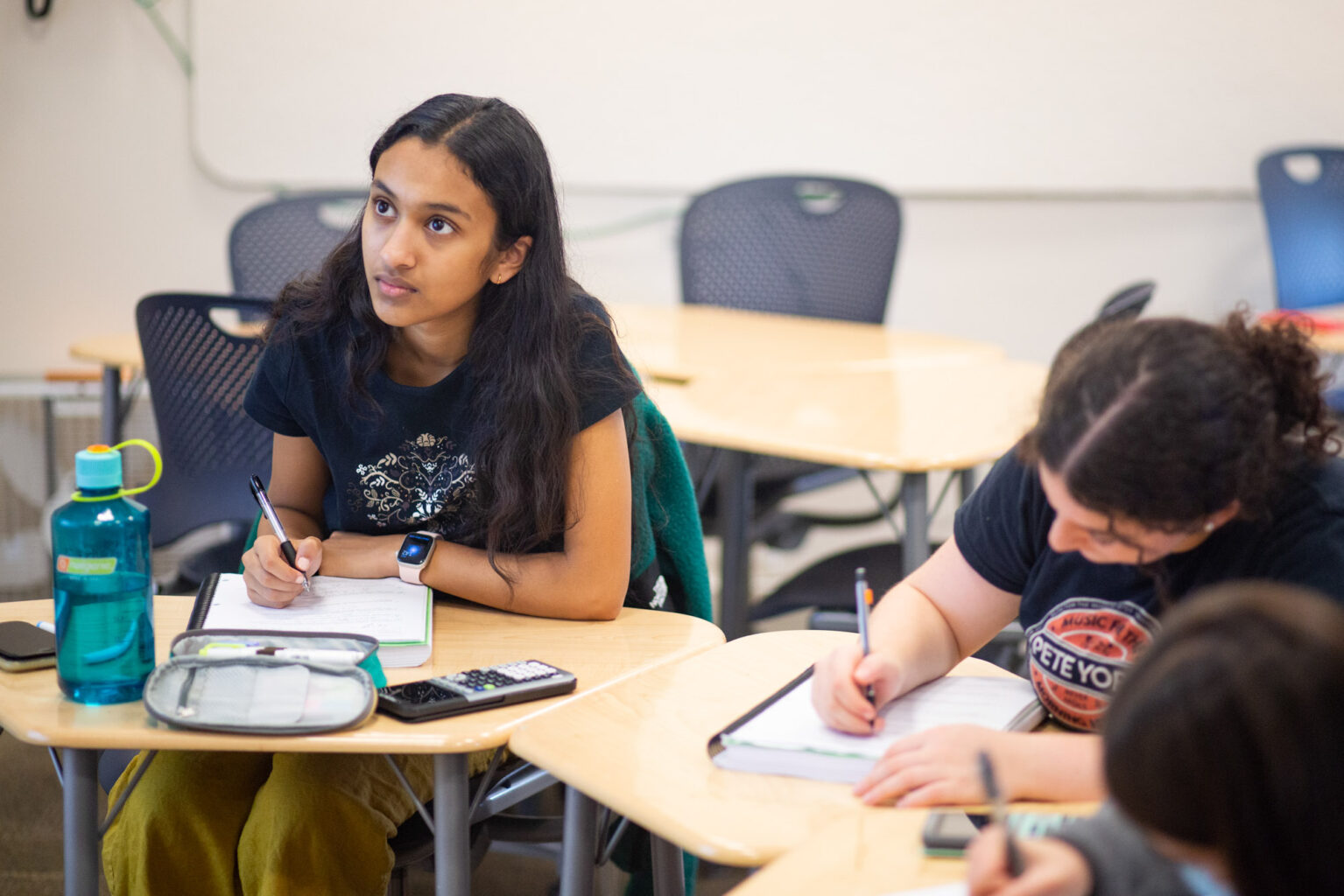 A girl writing in her notebook at her desk.