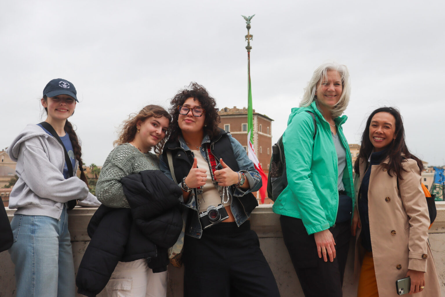 A group of women posing for a photo in front of the Italian flag.